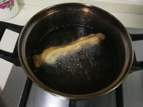 锅中油热，将面条两头用手捏着轻轻拉长，放入油锅炸