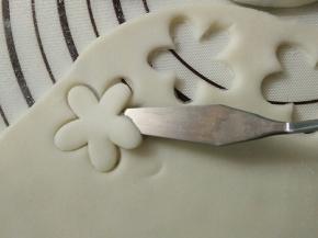 案板上撒少许糯米粉，将剩下的糯米团擀开，用模具压出花型。