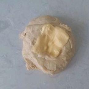 酵母液与面团糅合成出粗膜状态，加入软化好的黄油再次揉搓摔打