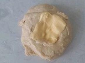 酵母液与面团糅合成出粗膜状态，加入软化好的黄油再次揉搓摔打