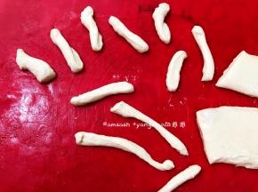 打开保鲜膜，手上抹少许油，把面团轻轻按开一下，按的时候别太用力，这样炸的时候油条才有张力，炸出来的油条才有孔洞，从中间切开，分成对面团，再切用条状，拿起一条面团，捏住两头稍微拉长，对折，再捏住两头，扭转一下，放入油中，放入油中用筷子快速翻动油条，让它能更好的受热均匀，这样炸出来的油条更有孔洞，上色也会更均匀