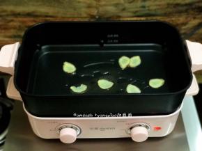 老姜用专门洗刷食物的刷子洗刷掉表面的泥土，不用去皮，切成薄片，多功能锅倒入少许油，足够煎鲈鱼就好，把姜片放在多功能锅上