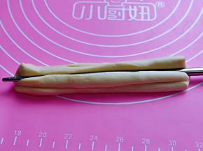 两两条面的两端捏在一起，用一根筷子放在条状面团的中间，压出印记，压的稍稍深一点！压好一面再反过来压痕迹！（两面都要用筷子压出印记）