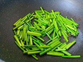 锅里加油，放韭苔快速翻炒。