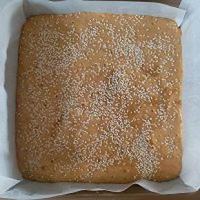 翻拌好的枣泥糊倒入八寸正方形模具，再撒上白芝麻，提起烤盘震两下震出大气泡