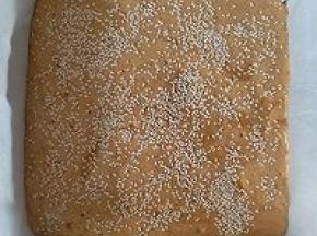 翻拌好的枣泥糊倒入八寸正方形模具，再撒上白芝麻，提起烤盘震两下震出大气泡