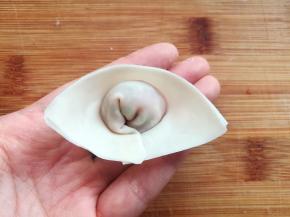 在馄饨皮上抹一点点水，把馄饨皮上下合起来，馄饨的右上角和右下角用少量的水贴合，就是一个好看的元宝形状了