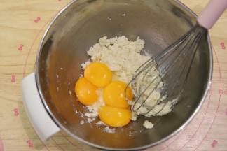 分离蛋黄和蛋清，蛋清倒入厨师机桶，放入冰箱冷冻，蛋黄磕入粉油奶混合物内。