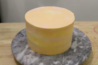 剩余的淡奶油分成两份，一份加入一滴红色食用色素，一份加入橘黄色食用色素，拌匀后抹在蛋糕表面，抹刀刮平。