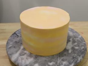 剩余的淡奶油分成两份，一份加入一滴红色食用色素，一份加入橘黄色食用色素，拌匀后抹在蛋糕表面，抹刀刮平。