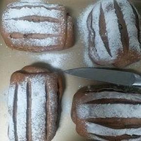 发酵好的面包胚表面筛上高粉，用锋利的刀划五刀，中间一刀，左右再各两刀