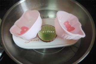 将学厨4寸KT硅胶模具放入煮沸水的锅里，倾斜角度，将粉色的马蹄浆用勺子放在蝴蝶结处，盖好盖子，蒸2分钟凝固。
