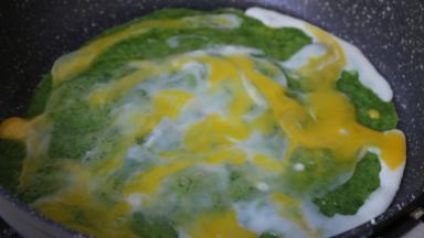 稍微凝固，打入一个鸡蛋，用铲子涂抹均匀在饼面上