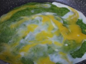 稍微凝固，打入一个鸡蛋，用铲子涂抹均匀在饼面上