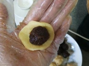 拿出面团分成14克一个滚圆，同时预热烤箱150℃。
拿一个面剂子在掌心中按压成片，放一个馅料，用虎口慢慢往往推至收口
