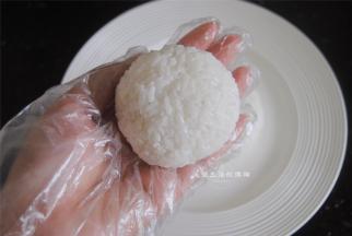 取大约50克的米饭，带着手套握成圆形，压扁一些，这是蜗牛的壳。