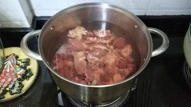煲里烧开水，放入姜片、料酒、葱扎、牛腩