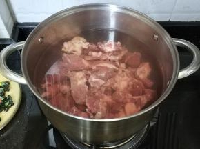 煲里烧开水，放入姜片、料酒、葱扎、牛腩