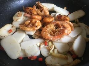 翻炒2分钟左右后倒入炸好的虾翻拌均匀；