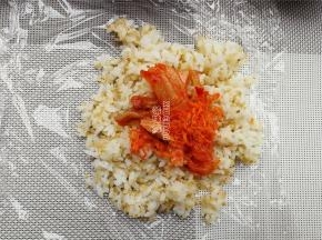 铺上保鲜膜，先取少许藜麦饭铺在保鲜膜上，再放入馅料。