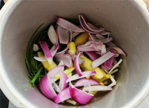 备一个高压锅，小葱铺入底部，分别放入姜片，洋葱块还有大块冰糖。