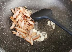 热锅倒油，把蒜瓣切片放入爆香，倒入大排肉翻炒下。