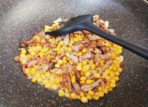 炒制出香味后，把玉米粒倒入翻炒片刻，撒入少许盐，生抽继续翻炒。