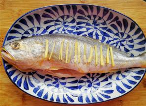 黄鱼身上划上几刀，把生姜块切点丝码入鱼身上（记住不是涂抹盐，而是放姜丝）。