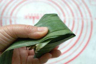 米放好了，把长出来的粽子叶折回来盖住糯米，检查一下，四周不能有米漏出来，包的时候不漏米，煮出来肯定更不漏米。