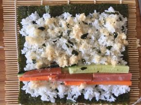 海苔铺在竹帘上，铺上米饭，摆放好菜菜、撒上肉松使劲卷起来～
