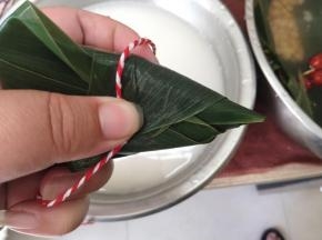 捏住收口的位置，轻轻的缠上绳子。