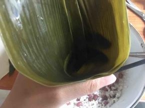 取两片粽叶，搭在一起叠压，将粽叶卷成一个圆锥状；