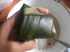 剩下的粽叶往另一边折叠，注意两侧的叶子全部折下去；