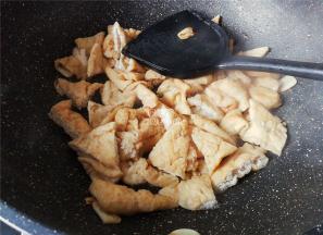 热锅倒油，蒜瓣切片倒入爆香，把切好的油豆干放入翻炒。