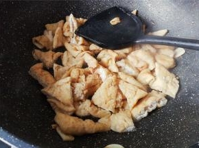 热锅倒油，蒜瓣切片倒入爆香，把切好的油豆干放入翻炒。