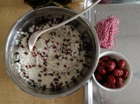 红豆倒入糯米里，然后淘洗几遍淘洗干净。沥干水分。红枣清洗干净沥干水分。棉绳冲洗一下。