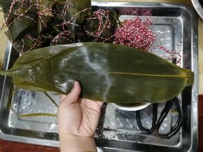 准备好一个托盘放粽子，准备好剪刀。两张粽叶，如图，光滑面朝上，大部分重叠放置，一头一尾放置。