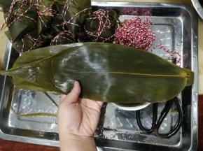 准备好一个托盘放粽子，准备好剪刀。两张粽叶，如图，光滑面朝上，大部分重叠放置，一头一尾放置。