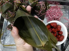 从中间位置，两手握住粽叶卷成漏斗形状。注意手指那个部位，漏斗底部要重合折上来，不然会漏米。