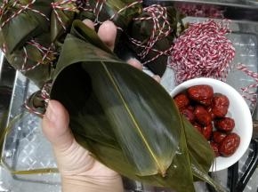 从中间位置，两手握住粽叶卷成漏斗形状。注意手指那个部位，漏斗底部要重合折上来，不然会漏米。