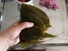 然后把多余的粽叶盖在糯米上。
