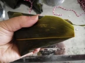 右手帮忙。把两边的粽叶往下压好，成三角状。