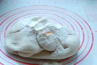 案板上撒上面粉，取出面团，把面团揉匀，充分排气。面粉要少量多次添加，等面团把面粉吃进去以后，再加入一些面粉，直到把面团揉成一个摸起来有些硬度，捏起来很结实的面团就好了。