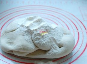 案板上撒上面粉，取出面团，把面团揉匀，充分排气。面粉要少量多次添加，等面团把面粉吃进去以后，再加入一些面粉，直到把面团揉成一个摸起来有些硬度，捏起来很结实的面团就好了。