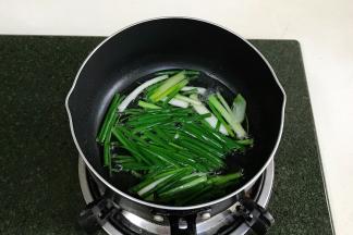 往锅中倒入适量的食用油，加入葱段，用小火加热炸葱油。