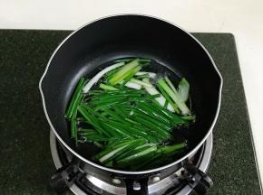 往锅中倒入适量的食用油，加入葱段，用小火加热炸葱油。