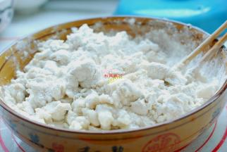 面粉放在盆子里，加入开水，先用筷子搅拌成大疙瘩，再放入适量的冷水，下手揉成一个柔软又光滑的面团。