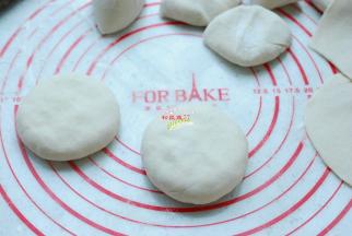 收紧口，翻过来按扁。收口要捏紧实，否则会漏馅出汤，煎制的时候锅底会黑乎乎一片，影响馅饼的美观。