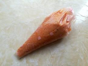 把胡萝卜虾肉泥装到裱花袋里，底部剪个手指大的口