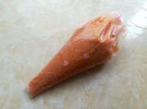把胡萝卜虾肉泥装到裱花袋里，底部剪个手指大的口